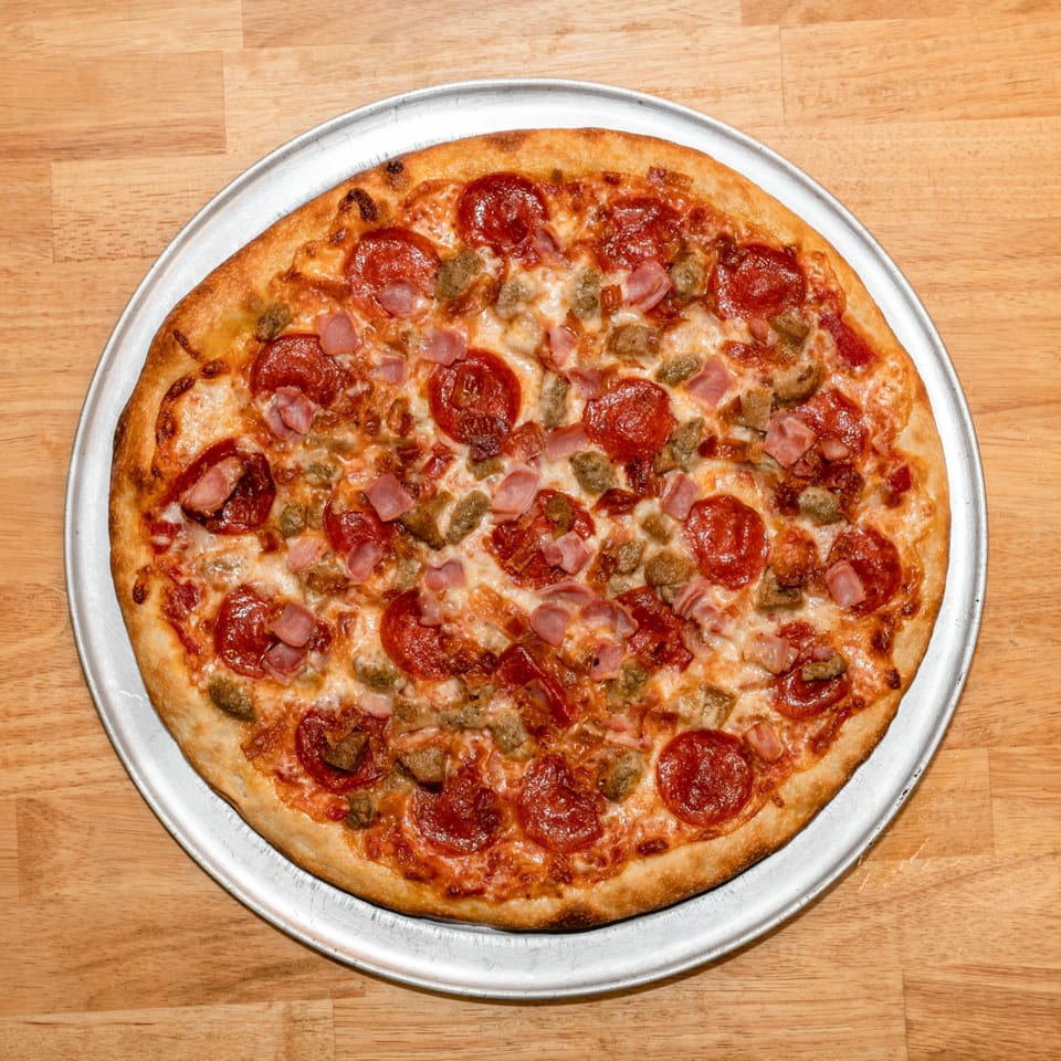 A freshly baked Papa V's Pizzeria meat lover's pizza with pepperoni, ham, and sausage.