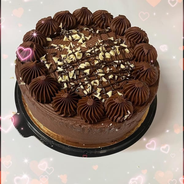 A rich chocolate cake from Papa V's Pizzeria, topped with chocolate frosting swirls and white chocolate shavings.